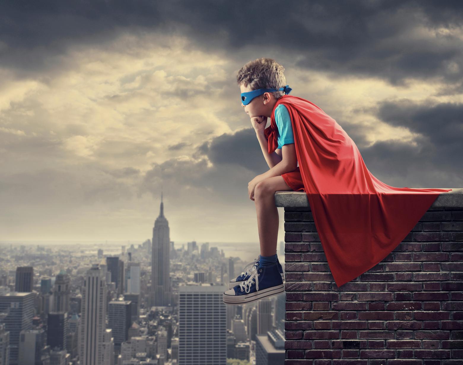 Little superhero sitting on top of wall